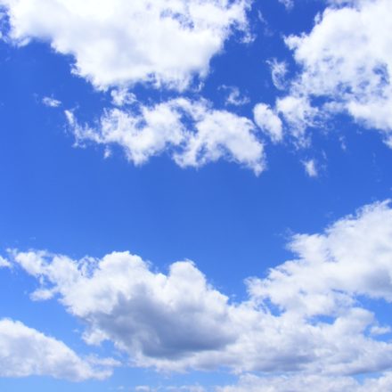 A bright blue sky with several fluffy white clouds