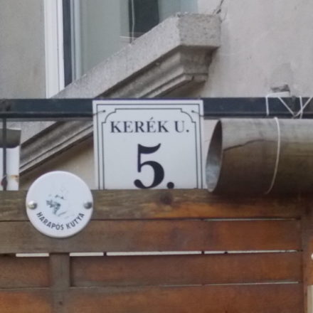 A black number 5 on a white placard on a building in Hungary