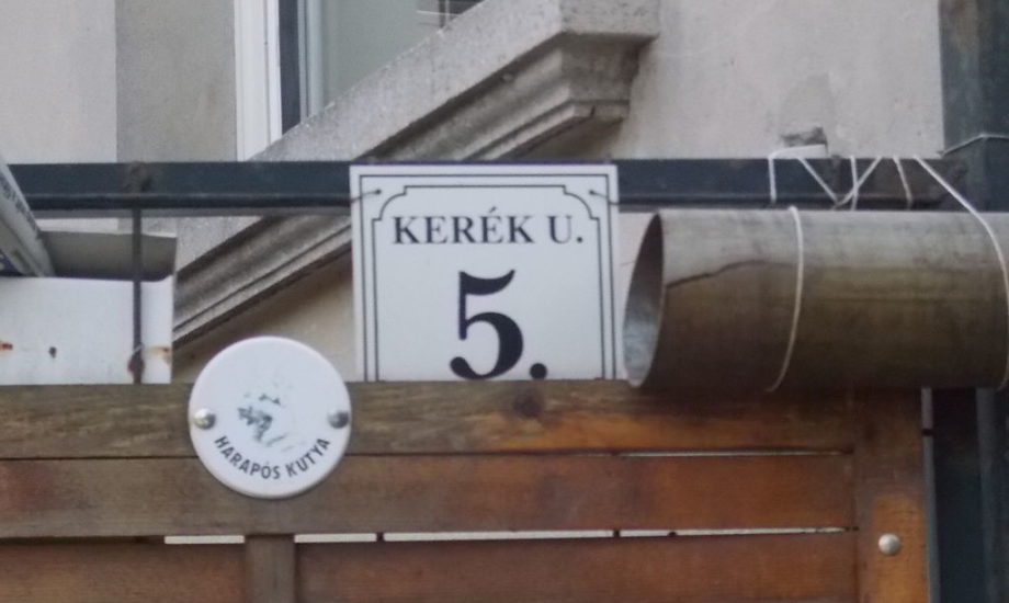 A black number 5 on a white placard on a building in Hungary