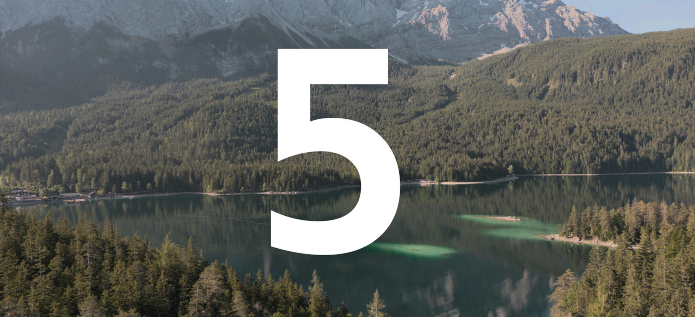 A photo of a lake in the alps surrounded by forests. A large number 5 is superimposed over the image for 5 for Friday.