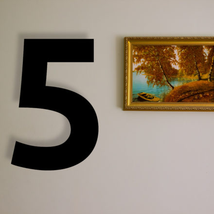 A color photo of an autumnal landscape in a golden frame and hanging on a wall.